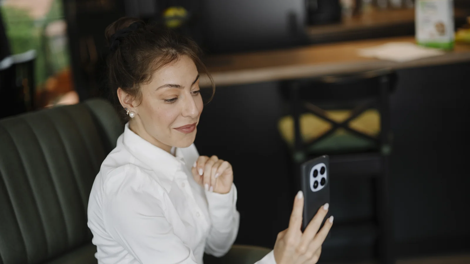 Femme regardant prudemment un écran de smartphone dans un café, ambiance rencontre en ligne
